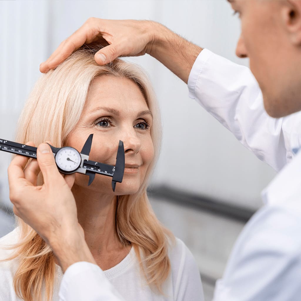 Doctor measuring patient's face with caliper during blepharoplasty consultation